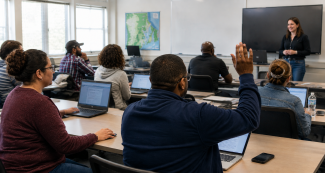Woman standing in front of a classroom of students sitting at desks with laptops